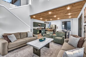 A modern living space with a sofa set, a coffee table, and a dining area with chairs. - Luxury Roof Top Cabin! Splashing Views! Pool! Hot Tub! Gaming Simulator! (Sevierville)