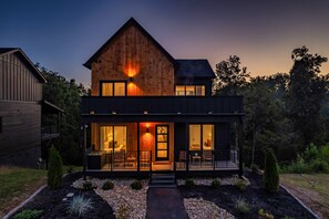 A two-story wooden house with a balcony and large windows. - Luxury Roof Top Cabin! Splashing Views! Pool! Hot Tub! Gaming Simulator! (Sevierville)
