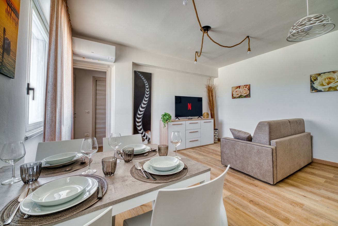 A dining area with a table set for four, a sofa, and a TV in the background.