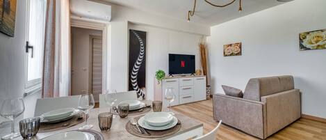 A dining area with a table set for four, a sofa, and a TV in the background.