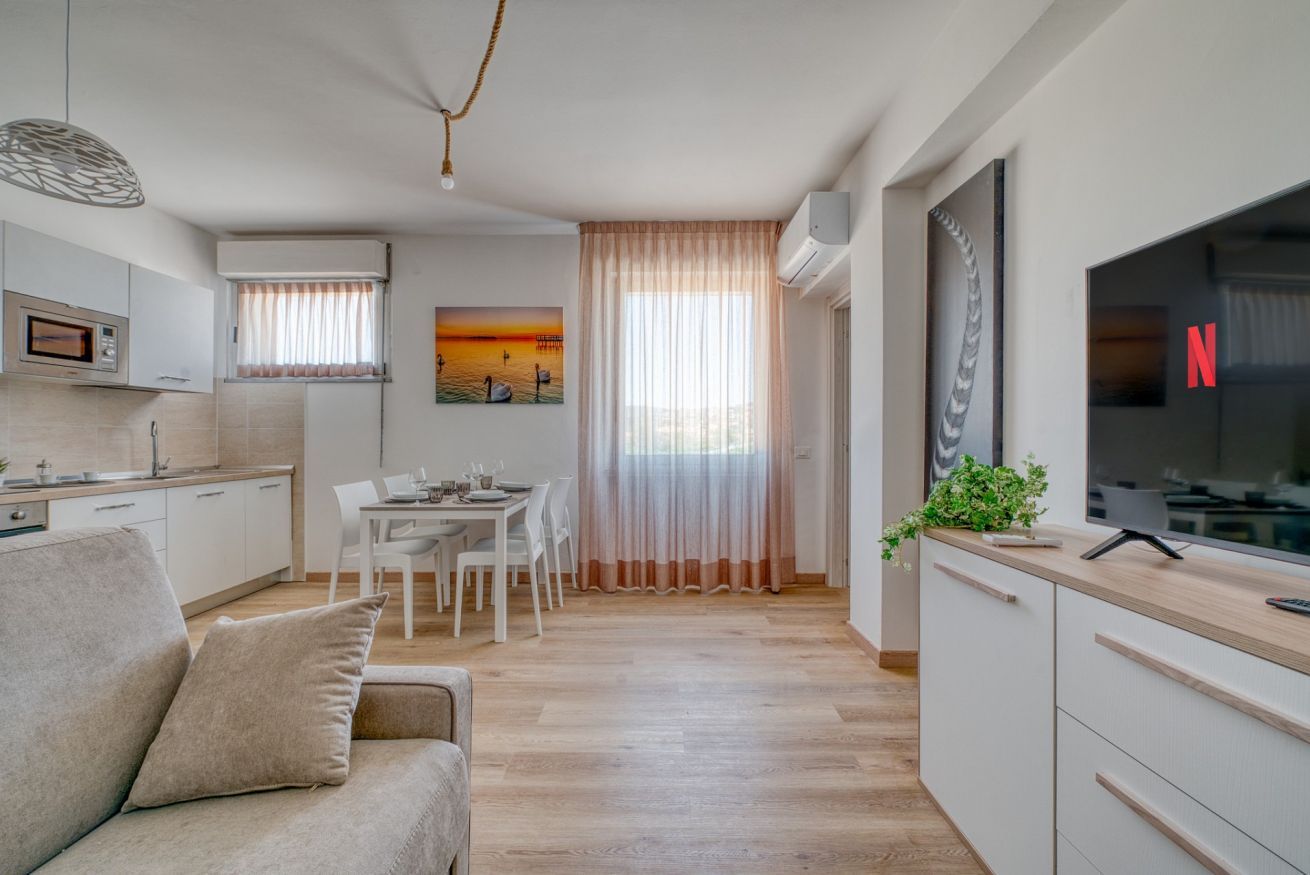 A modern apartment with a dining area, kitchenette, and a living room with a sofa.