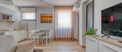 Un apartamento moderno con comedor, kitchenette y sala de estar con sofá.