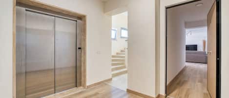 A hallway with a sliding door, a staircase, and a view into another room.