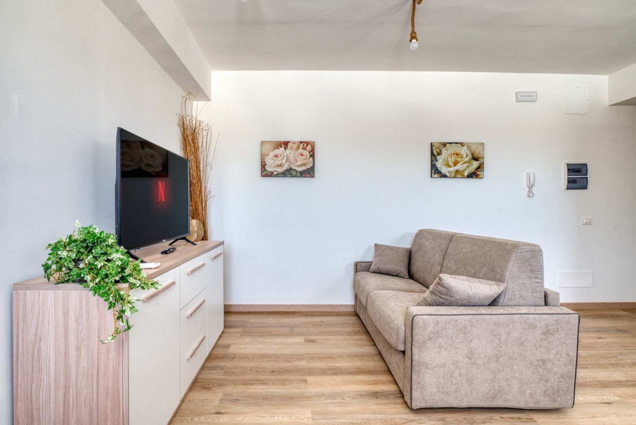 Ein modernes Wohnzimmer mit Flachbildfernseher, einer Couch und Wandbildern.