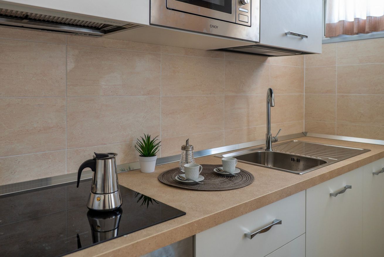 A modern kitchen with a black countertop, stainless steel appliances, a sink, and a small potted plant.