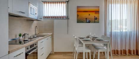 A modern kitchen with white cabinets, a microwave, and a dining area with a white table and chairs.