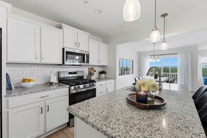 A modern kitchen with white cabinetry, granite countertops, stainless steel appliances, and pendant lighting. - New 3BR/3.5BA end unit townhouse under 3.5 mi from Beaver Stadium-full basement (State College)