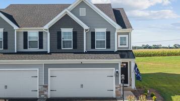 A two-story house with a garage, a stone foundation, and a flag.