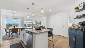 Una cocina moderna con una isla central, iluminación colgante y vistas al exterior.