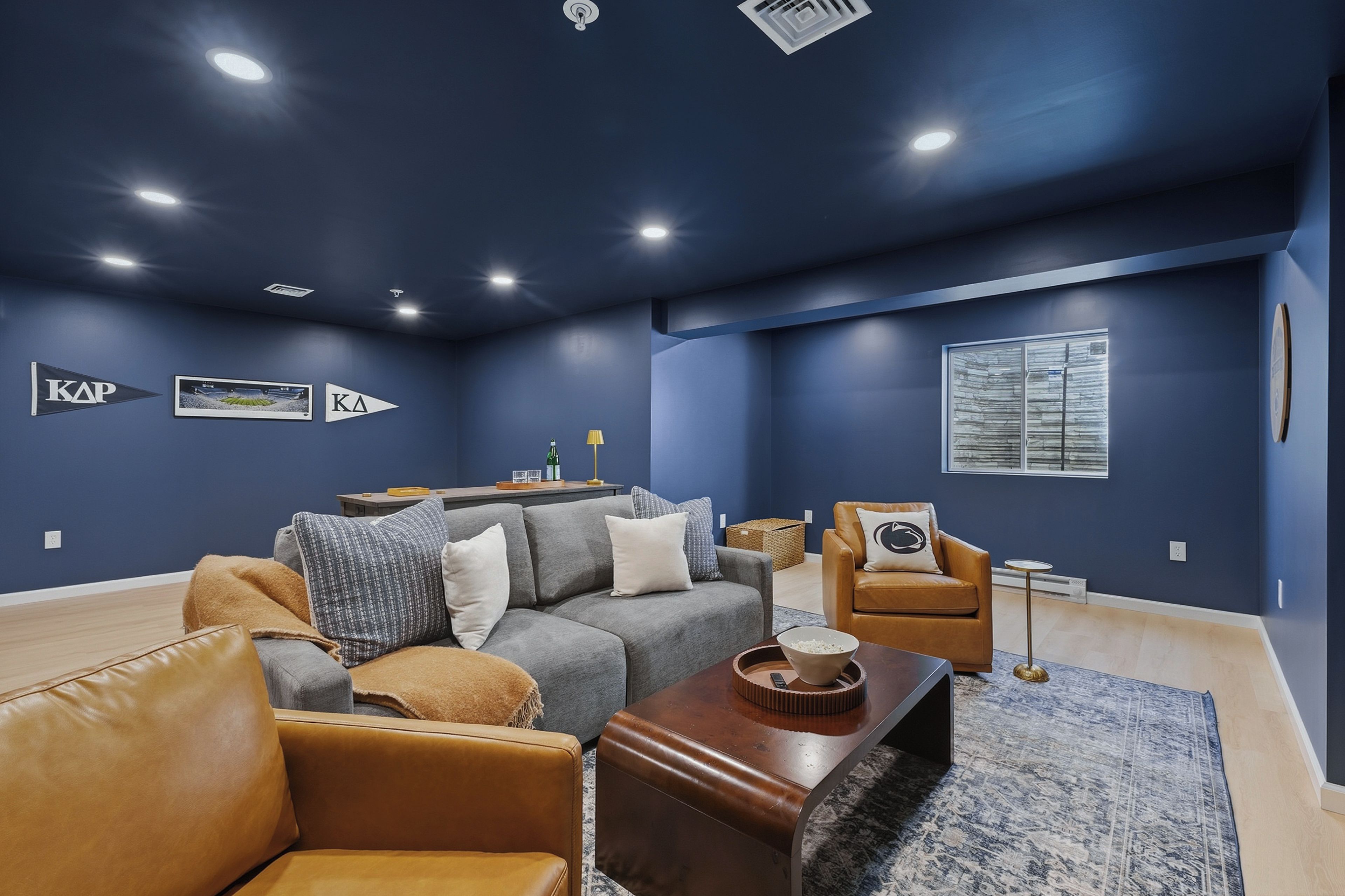 A modern living room with a dark blue wall, a leather sofa, a coffee table, and a small side table.