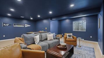 A modern living room with a dark blue wall, a leather sofa, a coffee table, and a small side table.