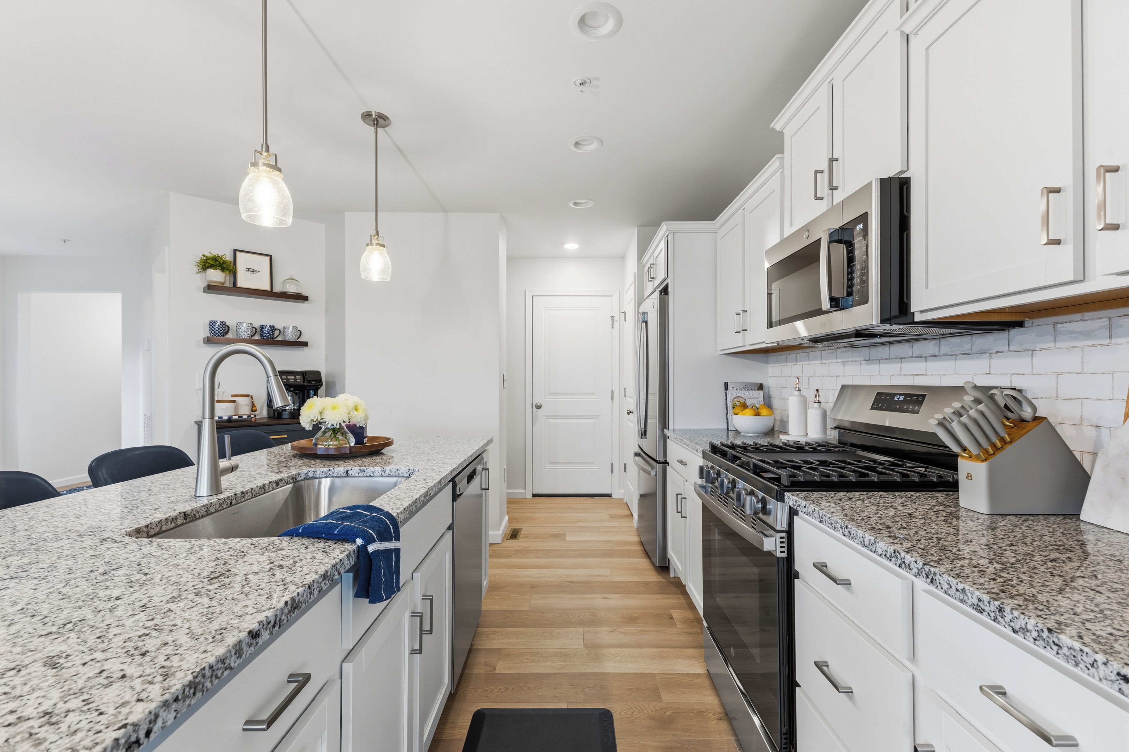 A modern kitchen with granite countertops, stainless steel appliances, and pendant lighting.