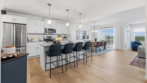 Una cocina moderna con una isla central, taburetes de bar y un área de comedor con vistas.