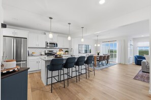 A modern kitchen with a central island, bar stools, and a dining area with a view. - New 3BR/3.5BA end unit townhouse under 3.5 mi from Beaver Stadium-full basement (State College)