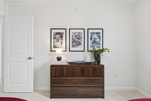 A room with a white door, a wooden console table with books and a lamp, and three framed photographs on the wall. - New 3BR/3.5BA end unit townhouse under 3.5 mi from Beaver Stadium-full basement (State College)