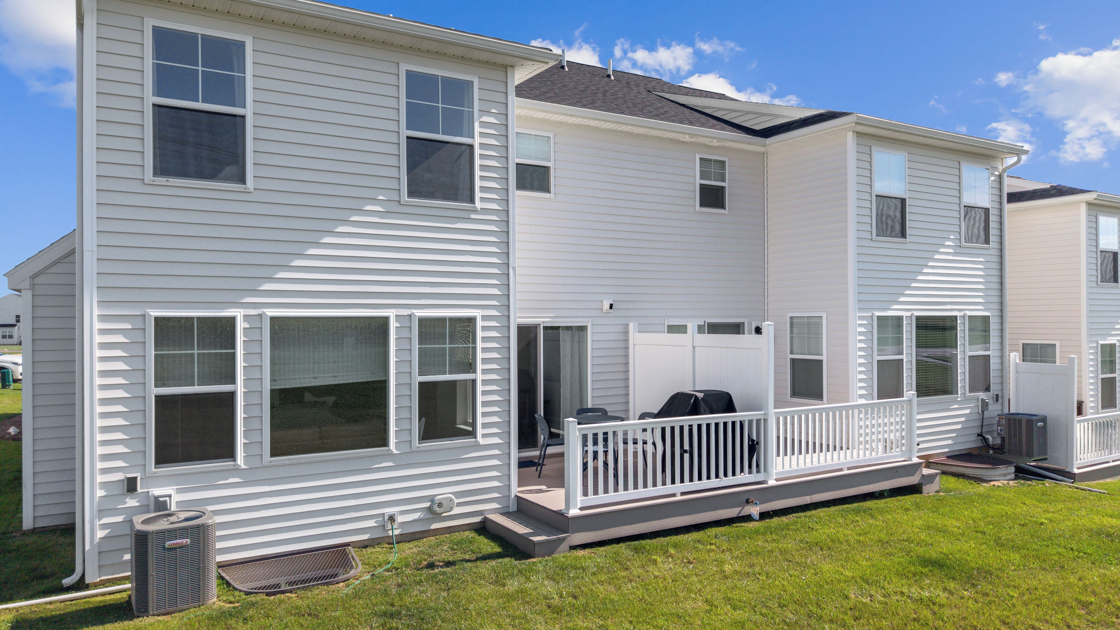 A two-story residential building with a covered patio area and a small outdoor seating space.