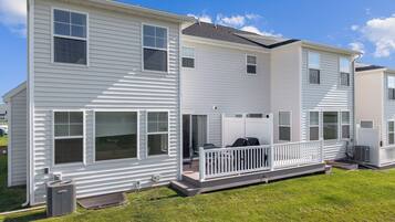 A two-story residential building with a covered patio area and a small outdoor seating space.