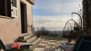 Une terrasse avec des meubles d’extérieur, un fauteuil suspendu et une vue sur le paysage.