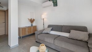 Un salon moderne avec un canapé gris, une petite table d’appoint et une lampe décorative.