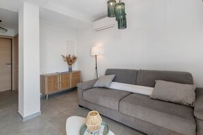 Un saló modern amb un sofà gris, una taula auxiliar i una làmpada decorativa.
