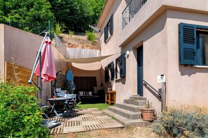 Ein Gebäude mit einer Terrasse, Sitzgelegenheiten im Freien und einer Treppe zum Eingang.