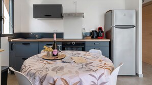 Une cuisine moderne équipée d’une table à manger pour deux personnes, d’un réfrigérateur et d’une machine à café.
