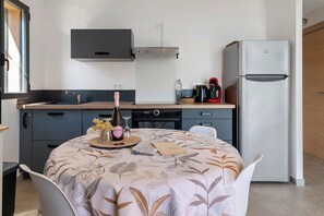 Una cuina moderna amb una taula de dinar preparada per a dues persones, un frigorífic i una cafetera.