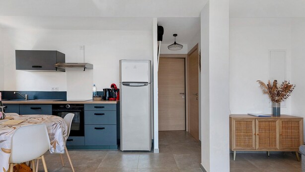 Une cuisine compacte équipée d’un réfrigérateur, d’une cuisinière et d’un coin repas avec une table et des chaises.