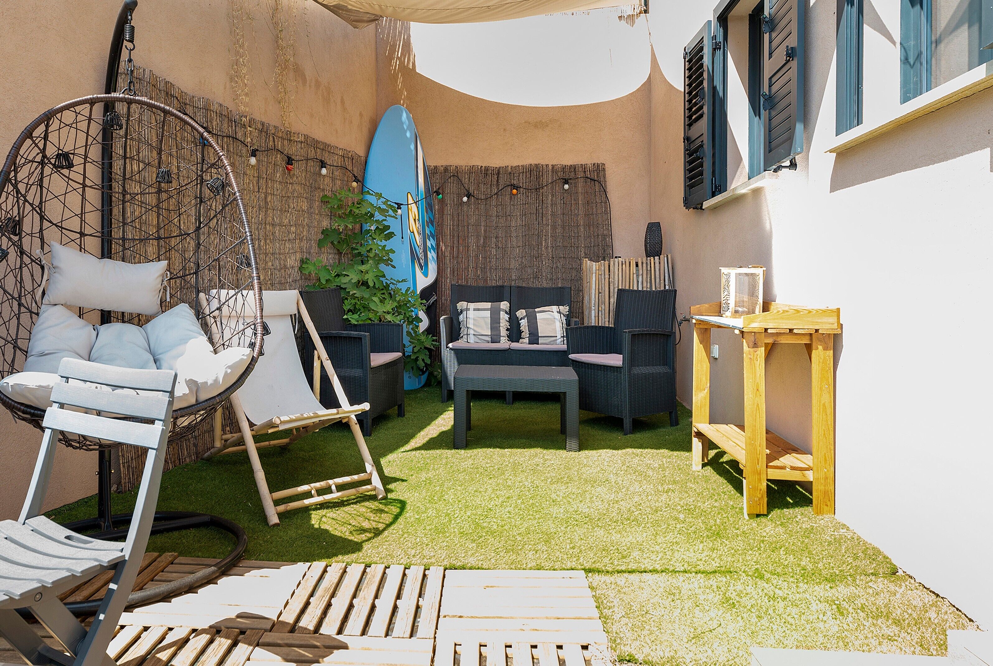 A cozy outdoor seating area with a swing chair, a table, and a bench.