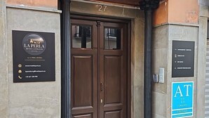 A hotel entrance with a double door, a signboard with hotel name and contact information, and a blue sign indicating AT services. - La Perla Reyes Catolicos Living: Standard Apartment (Granada)