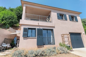 Ein zweistöckiges Gebäude mit Balkon, großen Fenstern und Garage.