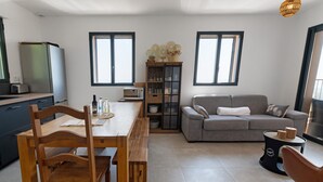 A modern kitchen with a dining table and chairs, a built-in oven, and a refrigerator.