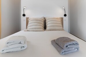 A bed with two pillows, a white bedspread, and two folded towels. - 'Villa Castagna' with Sea View, Private Terrace and Air Conditioning (Cervione)