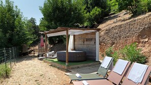 A sunlit outdoor seating area with lounge chairs and a small covered seating structure.