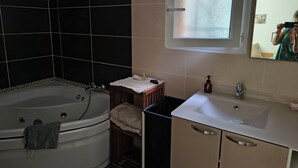 A bathroom with a bathtub, a sink, a mirror, and a window. - A room in a soothing setting (Lecci)