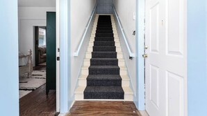 Eine Treppe mit Geländer, Teppichstufen und Holzdielen.
