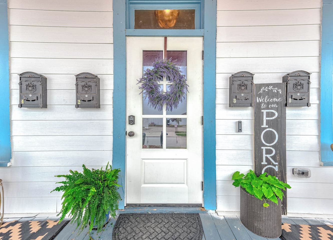 A white door with a blue trim, a wreath, and a sign that reads 'Welcome to our PORK.'