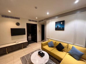 A modern living room with a sofa, a coffee table, a TV, and a painting on the wall. - Art suite (Riyadh)