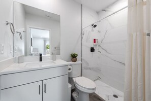Ein modernes Badezimmer mit Waschbecken, Spiegel, Toilette und Duschbereich.
