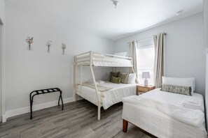 Een slaapkamer met twee stapelbedden, een nachtkastje met een lamp en een klein krukje.