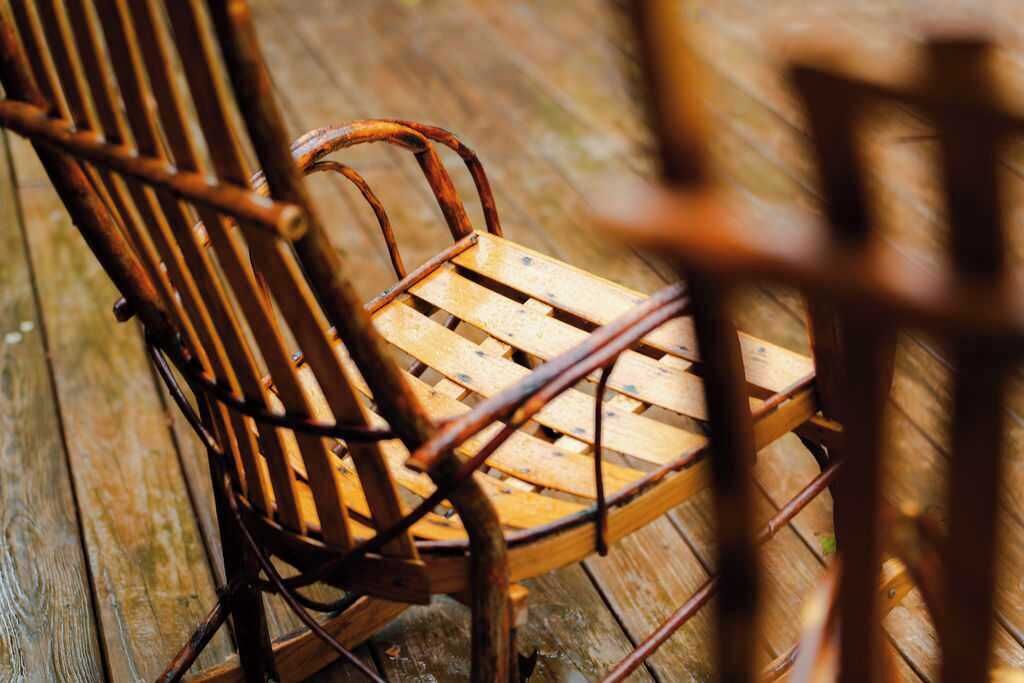 Una silla de madera con asiento y respaldo trenzados, sobre piso de madera.