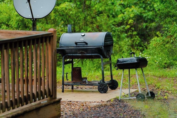 A portable grill with wheels, a satellite dish, and a metal container.