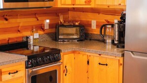 Una cocina con armarios de madera, un microondas, un tostador, una estufa y un refrigerador.