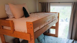 A bunk bed with a checkered top mattress and a blue quilted bottom mattress. - Unique Container Retreat With Creek Villa (McArthur)