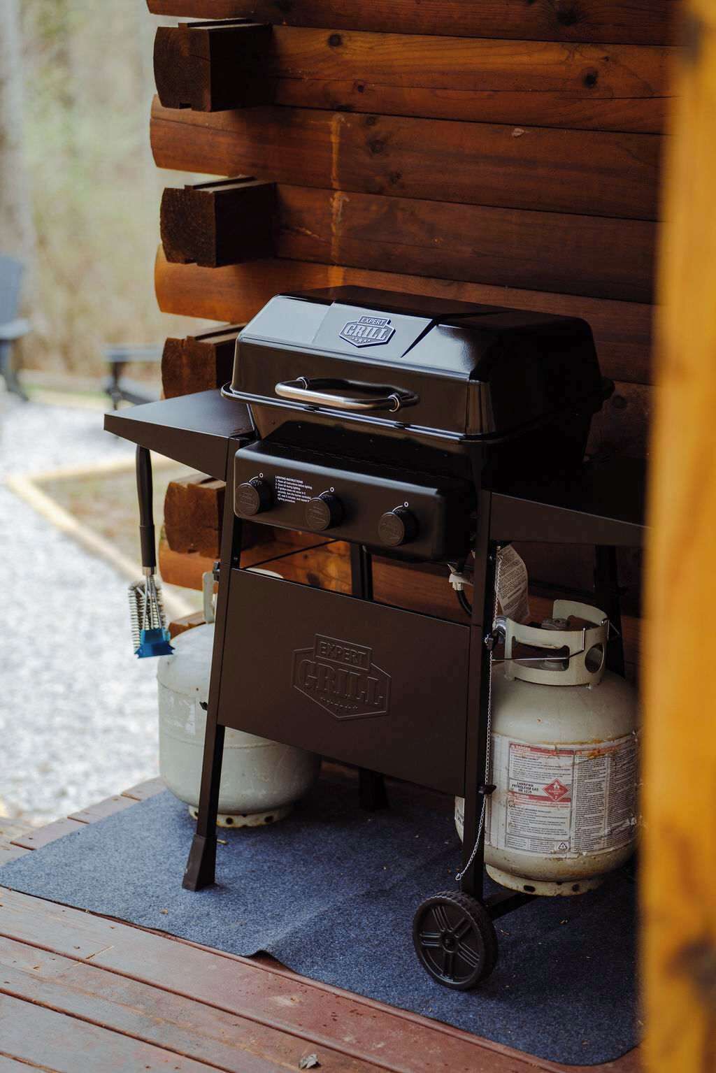 A portable grill with a gas tank and a metal cart.