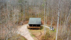 A cabin with a porch, surrounded by trees, and a dirt path leading to it. - Secluded Cozy Log Cabin Villa (McArthur)