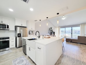 A modern kitchen with white cabinetry, stainless steel appliances, and pendant lighting. - Bright, Modern Lakefront 3 Bedroom Townhouse (Montgomery)