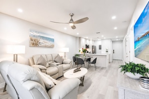 A modern living room with a sofa, a dining table, and a kitchen in the background. - Park Shore Resort - Dream Holiday Stays (Naples)