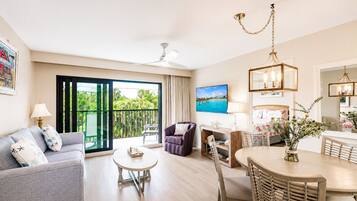 A hotel room with a balcony, a dining area, and a living space.