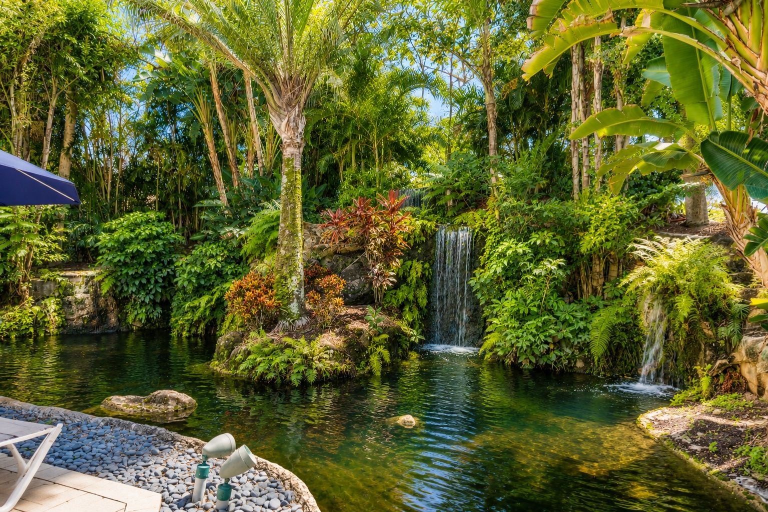 Un jardín sereno con un estanque, una cascada y abundante vegetación.